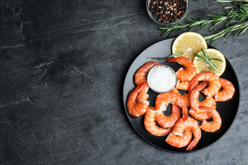 Delicious cooked shrimps with lemon and salt on dark grey table, flat lay. Space for text