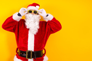 santa claus putting on sunglasses with yellow background