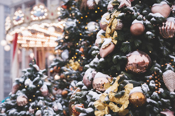 Big beautiful toys hang on a Christmas tree with sparkling garlands on a background of a carousel. New Year decorations on the streets of Moscow. Toning and artificial noise. Selective focus