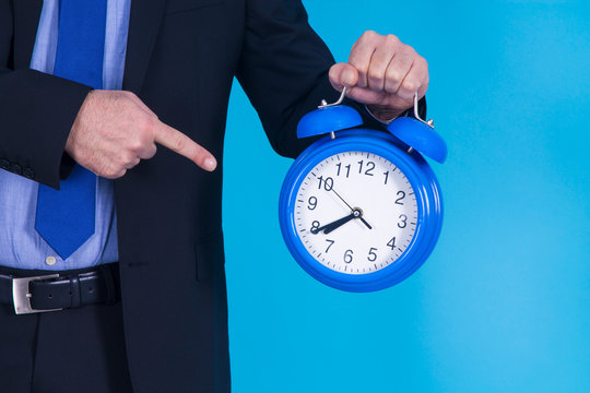 businessman pointing the alarm clock with his finger