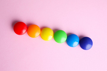 Bright magnets on pink background, flat lay. Rainbow colors