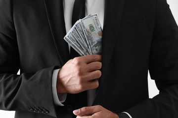 Man with bribe money on light background, closeup