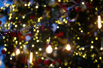 Christmas garland with bulbs on the background of a blurry evergreen spruce with toys and sparkling...