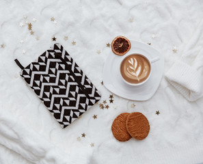 Notebook, coffee and cookies over oversize warm sweater. Minimal blogger background