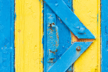 une vieille porte rouillée et des planches jaunes et bleues d'une cabane en bretagne