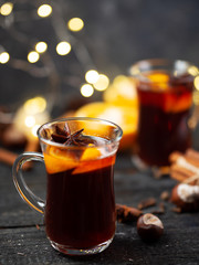 Traditional winter and Christmas hot drink mulled wine on a wooden table . With cinnamon, anise, tangerine