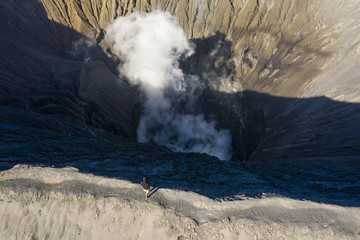 View from above, stunning aerial view of a person admiring the Mount Bromo with clouds of gases...