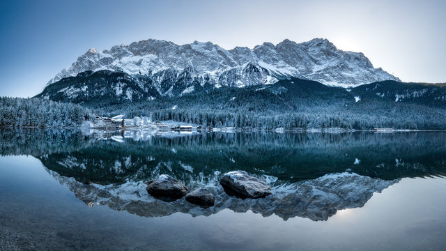 Panorama view Zugspitze reflection in eibsee in winter at sunrise snow. very cold, frost, ice evening hike, walk