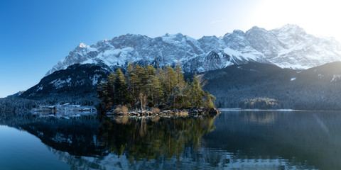 Naklejka premium Beautiful winter day with clear blue sky at the eibsee in south germany with view of the Zugspitze, highest german mountain, island Maximiliansinsel in the front