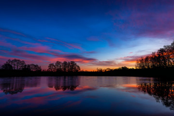 Sunset at czech countryside lake. Dramatic clouds.