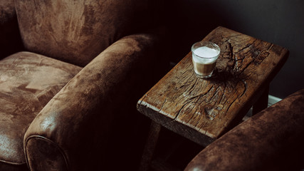 Fototapeta na wymiar Coffee on wooden table next to brown armchair