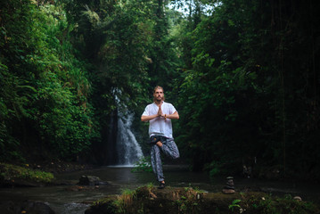 Obraz premium Yoga practice and meditation in nature. Man practicing near river