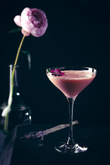 pink alcoholic cocktail decorated with roses and mint close-up on black background with copy space. pink drink for bar menu