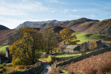 Fototapeta na wymiar Old derelict farm buildings in Autumn Fall landscape image in Lake District with Sleet Fell in background with epic light on the fells