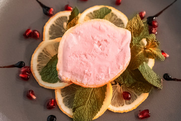 Homemade ice cream in the lemon with pomengrate seeds and peppermint leaves at marble gray background
