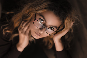 Fototapeta na wymiar Beautiful young women poses with glasses and her favorite books. Shiny pure skin, natural makeup