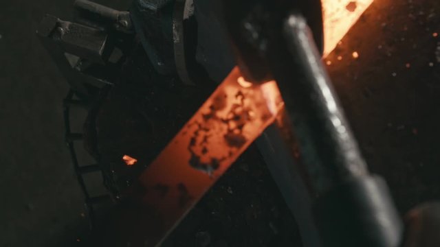 Forge workshop. Smithy manual production. Hands of smith with hammer hit on glowing hot metal, on the anvil, the forging process. Blacksmith makes iron products for manufacture of fireplace, stove.