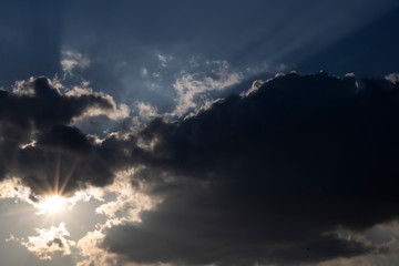 In the evening, sunlight is radiating through the clouds.