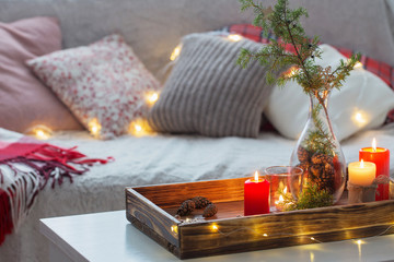 Composition of candles with juniper in vase on  white table agai