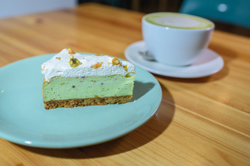 Fototapeta na wymiar Matcha latte and pistachio cheesecake on a large bright wooden table