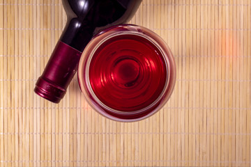 Glass and bottle of red wine on a tablecloth made of natural material