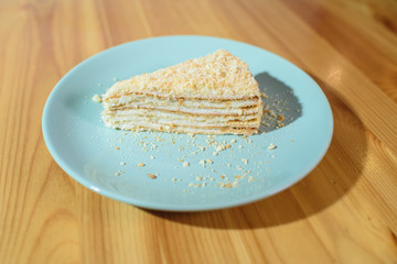 Slice of Napoleon cake on a large light wooden table