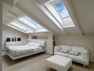 interior shot of a bedroom in the modern attic-room in the foreground the leather sofas with...