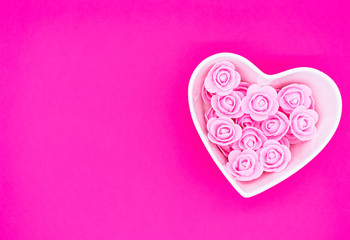 Pink roses in a heart-shaped box on a bright pink background. Valentines day background. Mother's...