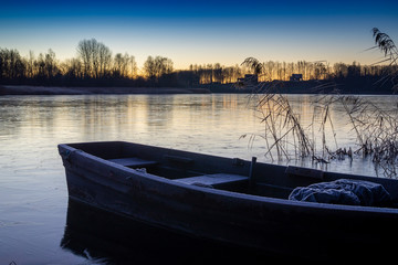 Naklejka na ściany i meble Wooden boat moored on a tranquil frozen lake