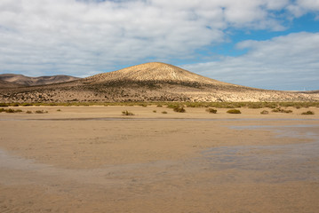 Hills on Playa de Sotavento - wide beach during low tide. Costa Calma, Fuerteventura, Canary Islands, Spain. 