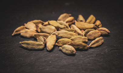 Close up view of cardamom seeds in black slate background. 