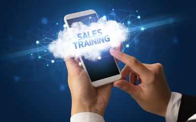 Female hand touching smartphone with SALES TRAINING inscription, cloud business concept