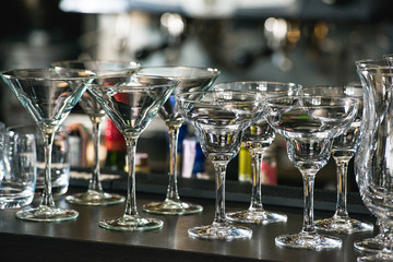 Glasses for a margarita, martini, grog and liqueur on a bar at restaurant, against the bar bar wall...