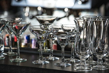 Glasses for a margarita, martini, grog and liqueur on a bar at restaurant, against the bar bar wall background.