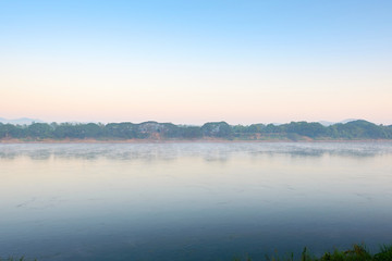 The image is a blurry sky with golden light at morning. The whole area was slightly covered with fog. This image is use as a background image.