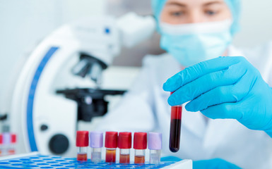 Blurred Woman in mask and gloves choosing blood sample