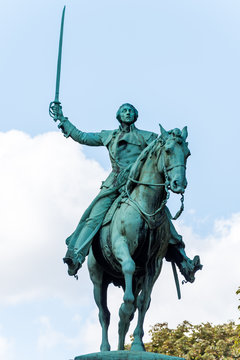 Bronze statue of Lafayette on his horse is set on a three-level granite base. He holds a sword in his right hand and the horse's reins in his left hand.