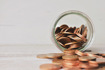 Euros, monedas en un frasco tumbado, esparcidas las monedas sobre la mesa