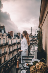 Young woman with blonde hair on Paris balcony in front of Eiffel Tower