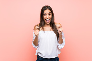 Young woman over isolated pink background celebrating a victory in winner position