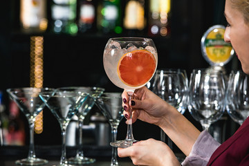 woman holding refreshing ruby red coctail with grape fruit isolated on a bar background