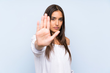 Young woman over isolated blue background making stop gesture with her hand