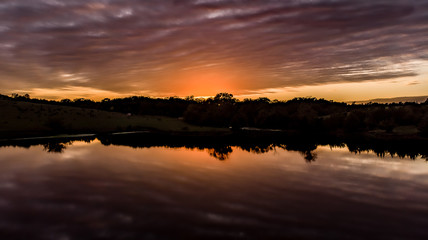 Golden hour sunset over a pond with clouds, sky, and trees