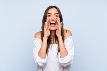 Young woman over isolated blue background shouting with mouth wide open