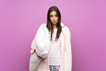 Young woman in pajamas and dressing gown over isolated purple background sad
