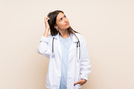 Young doctor woman over isolated background having doubts and with confuse face expression