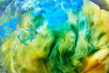 Abstract dancing colorful fume background. Clouds of smoke blue, green and yellow, a whirlwind of...
