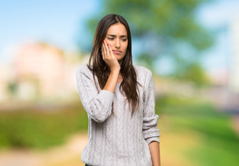 Young hispanic brunette woman with toothache at outdoors