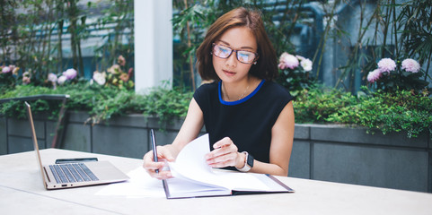 Occupied Asian woman checking notes