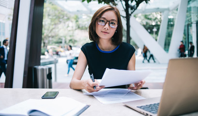 Asian businesswoman in glasses sitting with papers